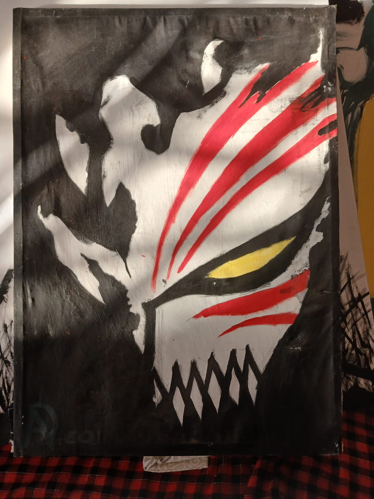 Ben Mungai holding a hammer beside a black, white, and red mask-like painting